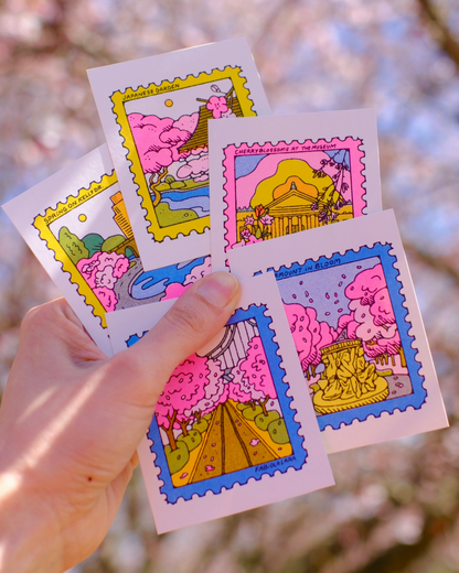 Colorful cherry blossom mini print designs held by a hand with a blurred natural background